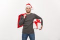 Christmas Concept - Young happy beard man holding santa bag and white present.