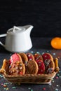 Christmas cookies in a basket, tangerines and a white teapot on a dark background