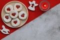 Christmas cookies with hearts on a plate on a red tablecloth, candle and Christmas decorations. Place for text Royalty Free Stock Photo