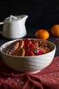 Christmas cookies, tangerines and a white teapot on a dark background with red textiles