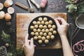 Christmas cookies. Top view of female hands holding, cooking raw unbaked dough balls in black plate with Christmas decoration