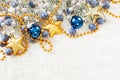 Christmas corner composition with green fir branch, gold garland, stars, blue glass baubles and berries on white snow background Royalty Free Stock Photo