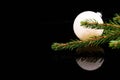 Christmas corner, focus on the spruce branch, white globe on black shiny surface