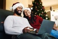 Christmas, couple and couch with laptop, credit card and together for finance, festive season and ecommerce in lounge Royalty Free Stock Photo