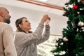 Christmas, couple and ornament on tree, happiness and smile together in lounge. Xmas, love and man with joyful woman Royalty Free Stock Photo