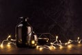 Christmas cozy dark modern interior - back and golden decoration - twinkle warm garland with elegant bottles on dark wood table. Royalty Free Stock Photo