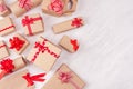 Christmas craft paper gifts with red ribbons closeup and bows on soft white wood table, top view, border. Royalty Free Stock Photo
