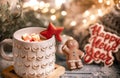 Christmas cup with marshmallows close up on blurred background with gingerbread cookies and lights Royalty Free Stock Photo