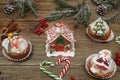 Christmas cupcakes, gingerbread house and muffin with Santa Claus, snowman, green spruce and candy cane on wooden background