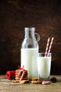Christmas dark background with snow and bokeh, copy space. Bottle, glass with milk for Santa, cookies, red rope, anise