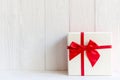 Christmas Day gift box with a red bow on white wall background, copy space. Merry Christmas and New Year Royalty Free Stock Photo