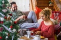 Christmas day morning breakfast with happy young adult couple in love enjoying coffee together - xmas tree and gifts - Home Royalty Free Stock Photo