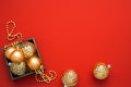 Gold baubles in different shapes and beads in the wooden box on the red background with copy space. Royalty Free Stock Photo