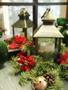 Christmas deco, candle lit lantern, evergreens, bells, pine cones, red poinsettia flowers,  mirror reflection Royalty Free Stock Photo