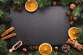 Christmas decor, aromatic spices, fir tree, oranges around slate board. Christmas or New Year stone background.