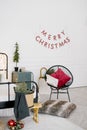 Christmas decor in the bedroom: a chair with pillows, pine and fir branches, a Christmas tree on the nightstand and the