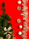 Christmas decor. Decorative fir-tree with silver decoration and festive brilliant silver balls on red background, vertical