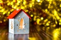 Christmas decor. A lamp in the shape of a house with glowing windows on a blurred background with a golden bokeh effect. Christmas Royalty Free Stock Photo