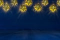 Christmas decor - lights shaped stars glow on indigo blue wooden background. Royalty Free Stock Photo