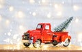 Christmas decor red retro car pickup truck on snow with fairy lights in bokeh Christmas tree. New Year greeting card. Cozy home Royalty Free Stock Photo