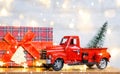 Christmas decor red retro car pickup truck on snow with fairy lights in bokeh Christmas tree. New Year greeting card. Cozy home Royalty Free Stock Photo