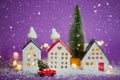 Christmas decor - red retro car on snow carries past houses with fairy lights in bokeh Christmas tree with gift boxes on roof. Toy Royalty Free Stock Photo