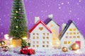 Christmas decor - red retro car on snow carries past houses with fairy lights in bokeh Christmas tree with gift boxes on roof. Toy Royalty Free Stock Photo