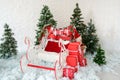 Christmas decor sleigh and red gift boxes with green christmas trees on snow, holiday decoration