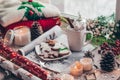 Christmas decor: Warm sweater, cup of hot cocoa with marshmallow, candy, candles and Christmas tree. Winter mood, decoration.