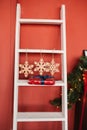 Christmas decor, white staircase, three snowflakes and a gift on the step against