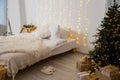 Christmas decorated bedroom interior with comfortable bed, Christmas fir tree and gift boxes on floor, copy space. Cozy Royalty Free Stock Photo