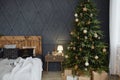 Christmas decorated bedroom interior with comfortable bed, Christmas fir tree and gift boxes on floor, copy space. Royalty Free Stock Photo