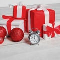 Christmas decorated red boxes gifts and alarm clock on wooden floor