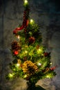 Christmas decorated small tree with red and gold decorations slowly lights up a light chain wrapped around a tree of yellow color Royalty Free Stock Photo