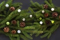 Christmas decoration background: cone, fir-tree branches, colorful glass balls on black background. Top view. Royalty Free Stock Photo