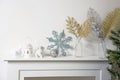 Christmas decoration: blue faux glitter snowflake, candle holder and porcelain white figurine bullfinch bird stand on the console Royalty Free Stock Photo