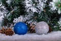 Christmas decoration blue and silver balls in a tree with tinsel and pinecone in snow Royalty Free Stock Photo