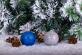 Christmas decoration blue and silver balls in a tree with tinsel and pinecone in snow Royalty Free Stock Photo