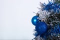 Christmas decoration blue and silver balls in a tree with tinsel and pinecone in snow