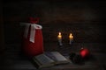 Christmas decoration with 2 Christmas candles, book, pine cones, red ball and Santa sack. Low-key lighting. Wooden background Royalty Free Stock Photo