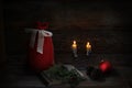 Christmas decoration with 2 Christmas candles, book, pine cones, red ball and Santa sack. Low-key lighting. Wooden background Royalty Free Stock Photo