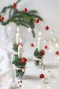 Christmas decoration. Candles in a glass jars decorated with fir and red berries on white table. Royalty Free Stock Photo