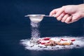 Christmas decoration and cookies.Woman hand sprinkling sugar on a cookies. Flour and spices for a baking on a dark backg Royalty Free Stock Photo