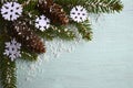 Christmas decoration. Decorative felt snowflakes, fir cones and snowy fir tree branch on light blue background with copyspace. Royalty Free Stock Photo