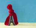 Christmas decoration with eiffel tower statue in red scraf and hat on colorful paper background. Holiday background with copy