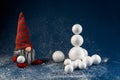 Christmas decoration elf, dwarf holding snowball and build snowman. Winter revels concept, holiday background scene Royalty Free Stock Photo