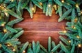 Christmas decoration. Fir tree frame witch christmas lights on rustic, wooden background. Royalty Free Stock Photo