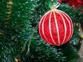 Christmas decoration in the form of a red ball made of threads with a golden ribbon hanging on a Christmas tree Royalty Free Stock Photo