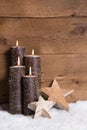 Christmas decoration: Four burning candles, stars and snow on wooden background Royalty Free Stock Photo