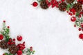 Christmas decoration. Frame of cones pine, twigs christmas tree, red berries and apples on snow with space for text. Top view, Royalty Free Stock Photo